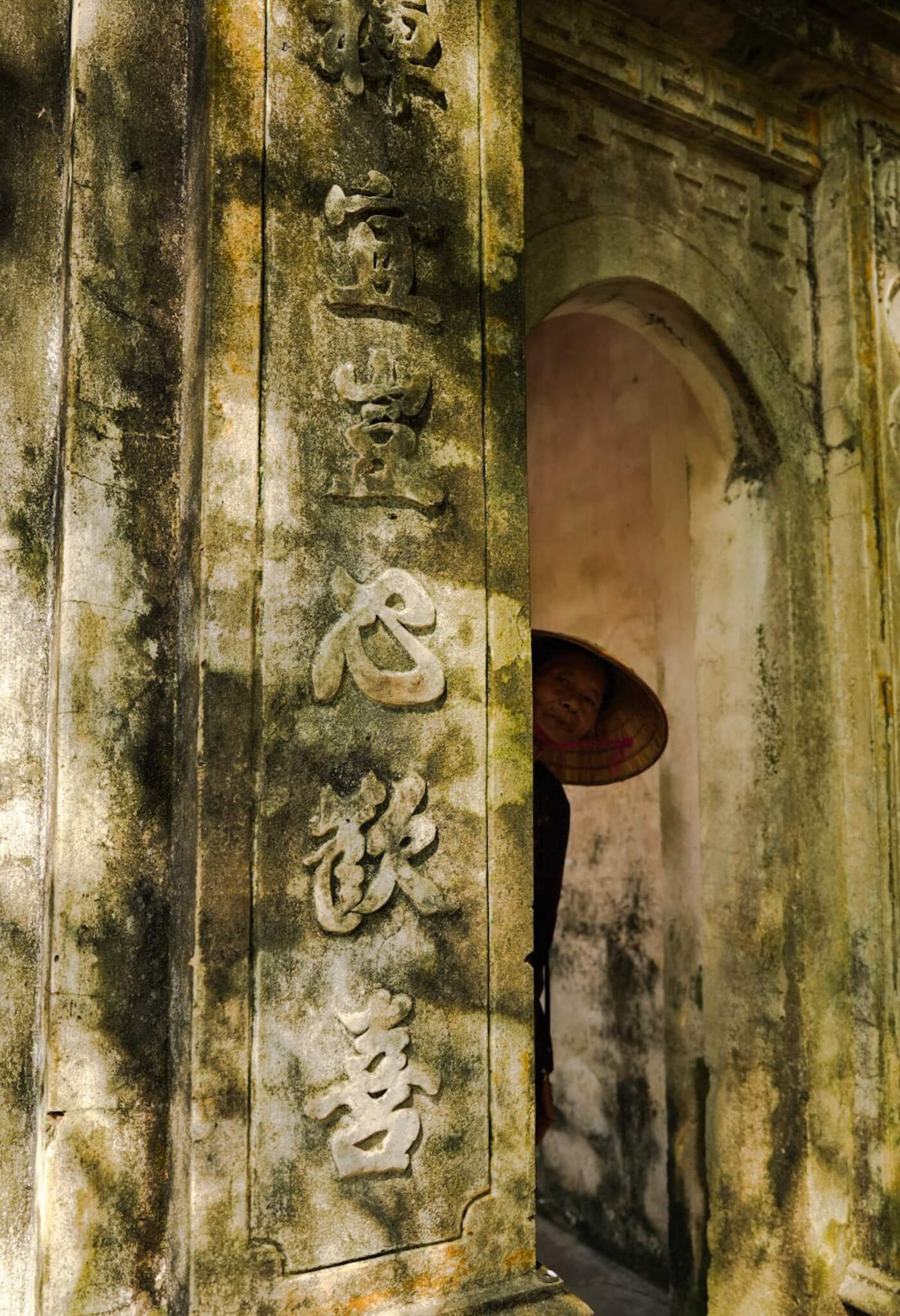 Woman peeking out the Buddhist temple Bich Dong in Vietnam